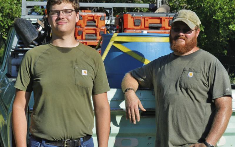 At left, Brennen Barber and his father, Ben Barber, take a break for the camera after a morning of work on Friday. ERICK MITCHELL | DISPATCH RECORD
