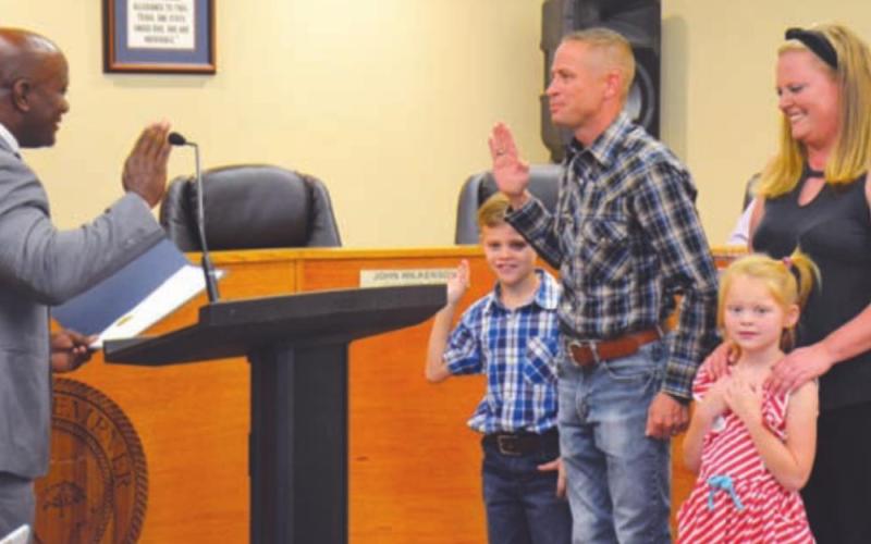 Mayor Dr. Keith Harvey, left, administers the oath of office on Tuesday to new Place II City Councilman Jared Jones. With Jones are his wife, Ashley; his daughter, Victoria; and his son, Jackson. DAVID LOWE | DISPATCH RECORD