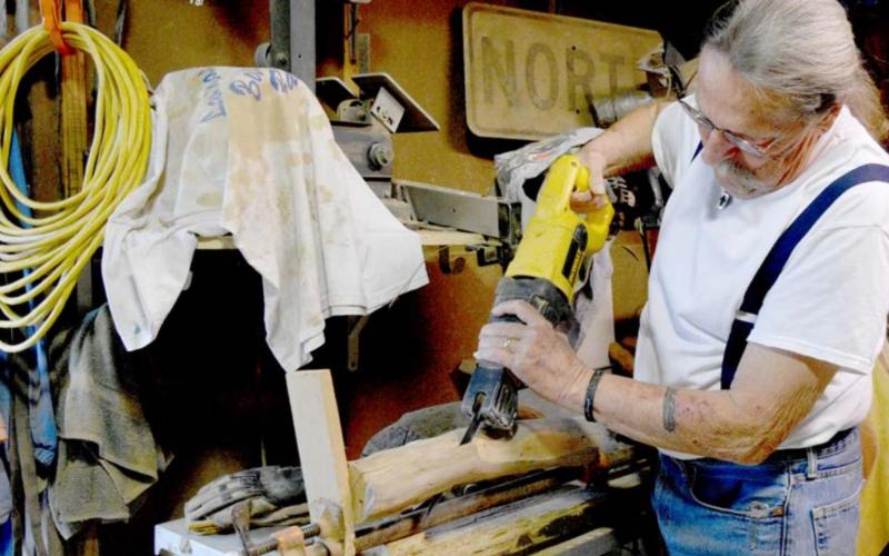 Allen Leske cuts a branch, preparing to assemble it into a cross. MADELEINE MILLER | DISPATCH RECORD