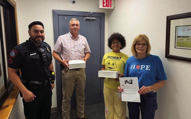 Dorothy Person, at right, and her granddaughter Nikita Olson deliver doughnuts to the Lampasas Police Department, where School Resource Officer John Resa and Assistant Chief Charlie Boswell accepted the treats for the department to share. COURTESY PHOTO