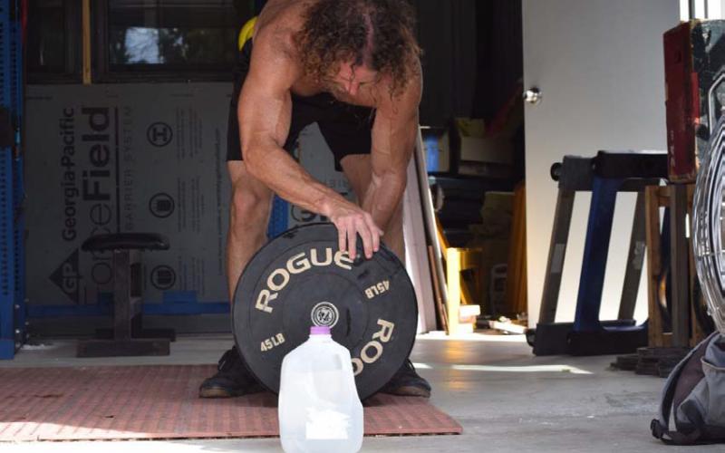 A functional fitness athlete does an open-air workout on a hot summer’s day, but not without his gallon jug of water. The human body can lose several pounds of water through sweat and exhalation during high activity. ALEXANDRIA RANDOLPH | LAMPASAS DISPATCH RECORD
