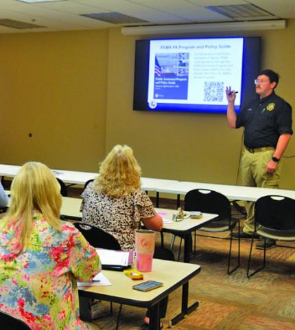 TDEM Regional Recovery Coordinator Matthew Weeks provides a presentation to the Lampasas County Commissioners Court and representatives of other local entities to outline the availability of FEMA public assistance to cover May’s flooding events. ERICK MITCHELL | DISPATCH RECORD