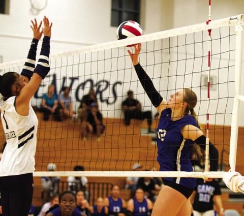 Kari Kepler, right, tips a ball over the hands of a Shoemaker player in the Lady Badgers’ win on Tuesday night.