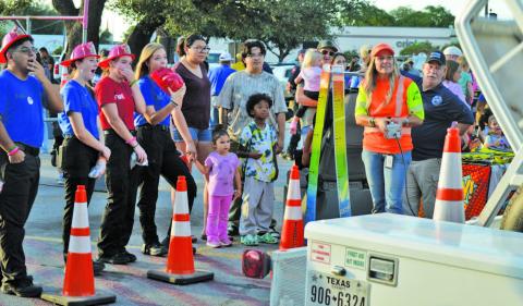 At left, Lampasas High School fire and EMT students look in awe at the Texas Department of Transportation’s demonstration showing how an unrestrained child moves freely in the vehicle during a rollover accident. The simulation helped emphasize the imporantce of having a properly-fitted child safety seat. For more photos from Tuesday’s National Night Out event in Lampasas