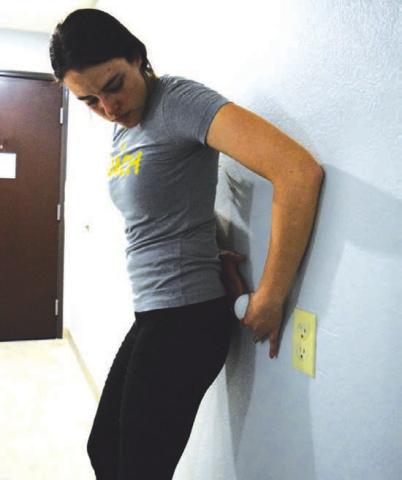 A lacrosse ball can be used at home or on the go as a self-massage tool. Here, columnist Alexandria Randolph demonstrates how to apply pressure to muscles in the upper glutes while standing against a wall. ALEXANDRIA RANDOLPH | DISPATCH RECORD