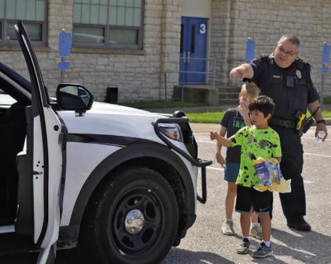 Lampasas Police Department Patrol Sgt. Steve Sheldon shows children around a police vehicle during the Lampasas County Higher Education Center’s “Case of the Missing Mascot” class on Monday. ERICK MITCHELL | DISPATCH RECORD