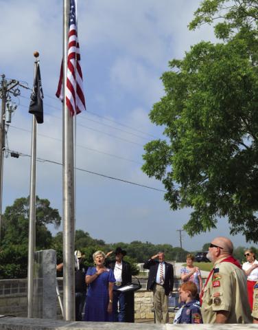 Those in attendance at Kempner’s Memorial Day ceremony pay their respect to the flag as Alicia Straley sings the national anthem. ERICK MITCHELL | DISPATCH RECORD