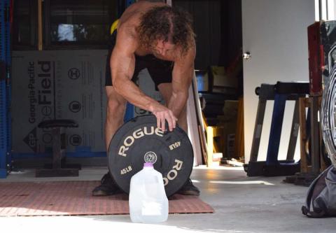 A functional fitness athlete does an open-air workout on a hot summer’s day, but not without his gallon jug of water. The human body can lose several pounds of water through sweat and exhalation during high activity. ALEXANDRIA RANDOLPH | LAMPASAS DISPATCH RECORD