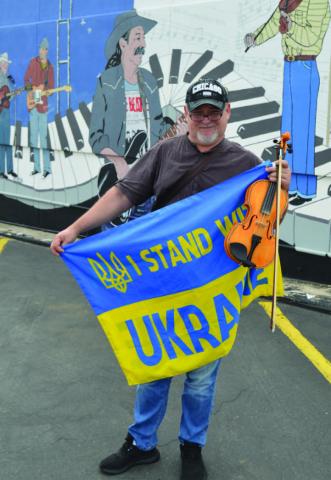 Ukrainian violinist Victor Voloschuk poses in front of a Lampasas music mural. ERICK MITCHELL | DISPATCH RECORD