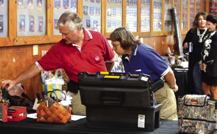 David (left) and Debra Peters inspect silent auction items on display at the Lampasas County Livestock Association’s Reverse Raffle fundraiser on Saturday. ERICK MITCHELL | DISPATCH RECORD