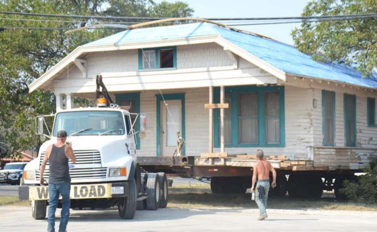 King House Moving crew member Rodney Henshaw, in black shirt, gives guidance on Friday as company owner John King transports a house from 105 W. First St. to the house’s new location, 374 Supple Dr. Also pictured is crew member Shane Paduch. DAVID LOWE | DISPATCH RECORD