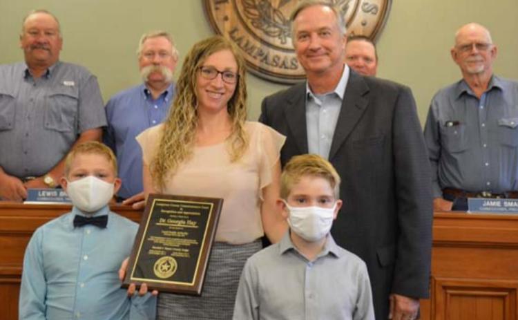 Dr. Georgia Hay stands with her sons Chase, left, and Jacob, along with County Judge Randy Hoyer on Monday, when the physician was honored for her service to the community. Back row from left are county commissioners Mark Rainwater, Lewis Bridges, Jamie Smart and Bobby Carroll. MONIQUE BRAND | DISPATCH RECORD