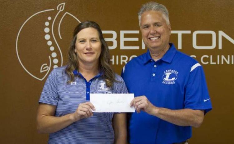 Jan Brister receives a check from Craig Benton for $500 that will go toward improvements for the athletic training department. HUNTER KING | DISPATCH RECORD