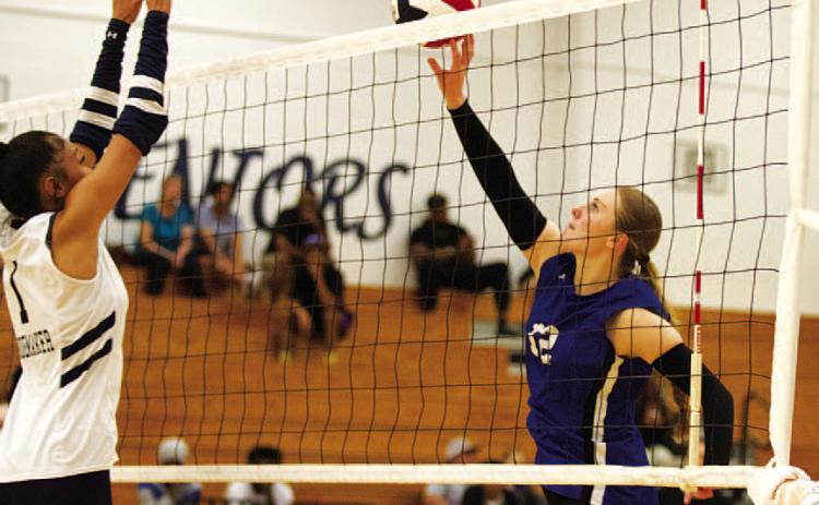Kari Kepler, right, tips a ball over the hands of a Shoemaker player in the Lady Badgers’ win on Tuesday night.
