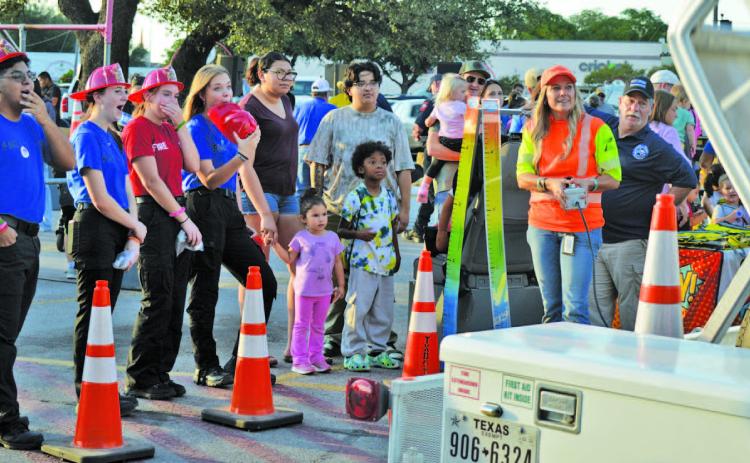At left, Lampasas High School fire and EMT students look in awe at the Texas Department of Transportation’s demonstration showing how an unrestrained child moves freely in the vehicle during a rollover accident. The simulation helped emphasize the imporantce of having a properly-fitted child safety seat. For more photos from Tuesday’s National Night Out event in Lampasas