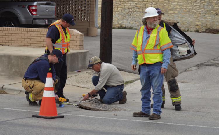 ERICK MITCHELL | DISPATCH RECORD Lampasas Fire Department firefighters and Atmos Energy representatives look to investigate a possible natural gas leak underneath a manhole on Fourth Street between Live Oak and Western Avenue.