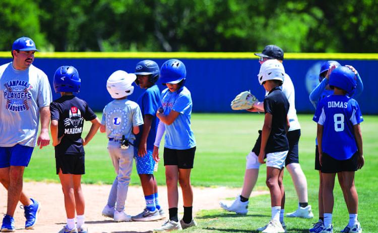 Assistant coach Jaden Napolez, left, talks to some campers about base running this week. HUNTER KING | DISPATCH RECORD