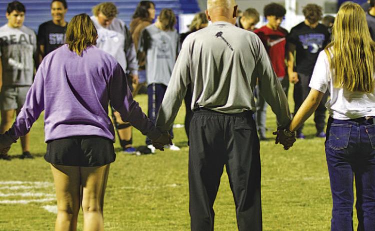 Students from Lampasas and Lometa gather on Badger Field to pray at the conclusion of the Fields of Faith event Wednesday night. The local chapter of Fellowship of Christian Athletes hosts the annual night of student-led prayer and fellowship. HUNTER KING | DISPATCH RECORD