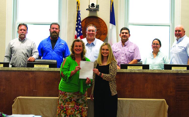 Becky Sims, left, and Kayleigh Stanley pose with the city council after being recognized for Professional Municipal Clerks Week at Monday’s meeting. HUNTER KING | DISPATCH RECORD