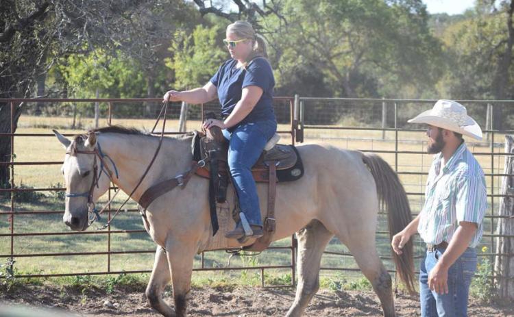 U.S. Armed Forces veteran Krystal Ybarra, a Camp Cowboy program participant, rides “CD” around an arena under the supervision of Lane Robison, program director. Alexandria Randolph | dispatch record