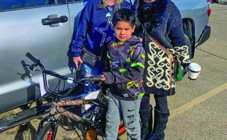 David Flores, center, poses for a photo with his new bicycle, a gift from Vicki Taylor and Wendi Boylan Wulstein, left to right. COURTESY PHOTO