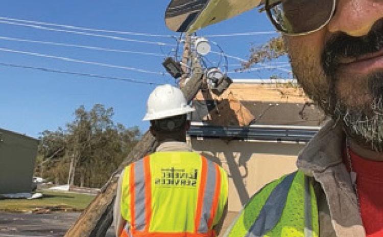 Armando Rosales poses for a work selfie that includes in the background a broken power pole caused by heavy winds from Hurricane Helene in Georgia. Rosales spent more than a month on the job assisting in restoration efforts after Hurricanes Helene and Milton struck the Southeast earlier this year. courtesy photo