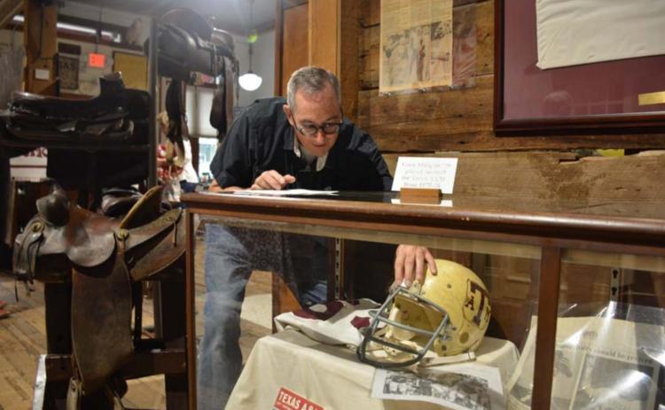 Museum board member John Fingerhut props up a Texas A&amp;M football helmet at the Lampasas County Museum on Friday morning. The exhibit opens to the public this week. MONIQUE BRAND | DISPATCH RECORD