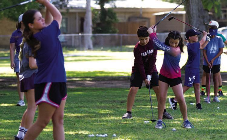 A group of young golfers practice on the driving range at Hancock Park Golf Course on Tuesday at golf camp. HUNTER KING | DISPATCH RECORD