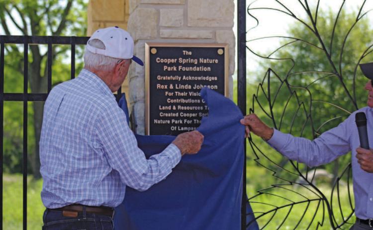 Rex Johnson, assisted by Harrell Clary at right, unveils the plaque dedicating Cooper Spring Nature Park and recognizing Johnson and his wife, the late Linda Johnson, for their work and generosity in making the park a reality. JOYCESARAH MCCABE | DISPATCH RECORD