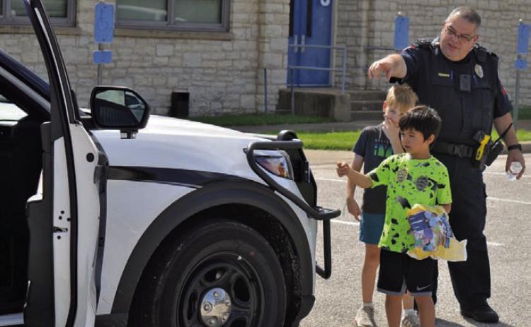 Lampasas Police Department Patrol Sgt. Steve Sheldon shows children around a police vehicle during the Lampasas County Higher Education Center’s “Case of the Missing Mascot” class on Monday. ERICK MITCHELL | DISPATCH RECORD