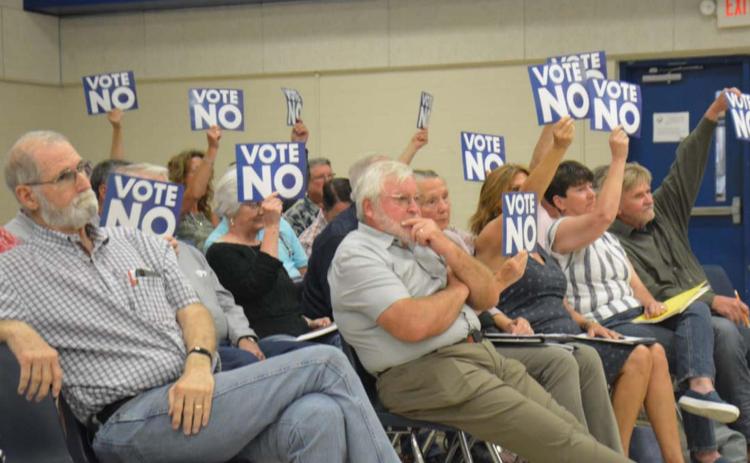 Audience members hold signs in opposition to tax incentives for a solar farm project under consideration by the Lampasas Independent School District. MONIQUE BRAND | DISPATCH RECORD