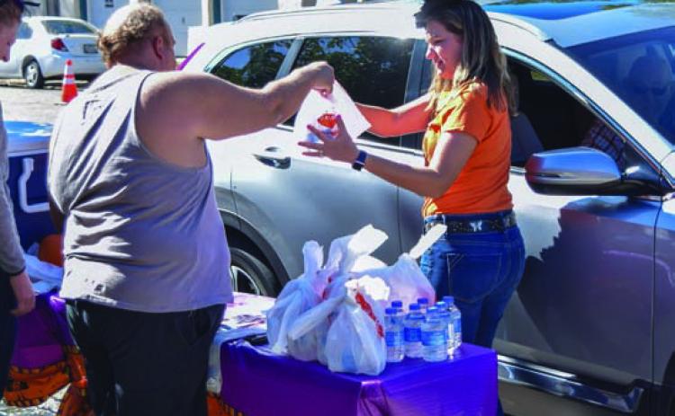 Volunteers help distribute barbecue sandwiches curbside at a previous BBQ for Books event. FILE PHOTO