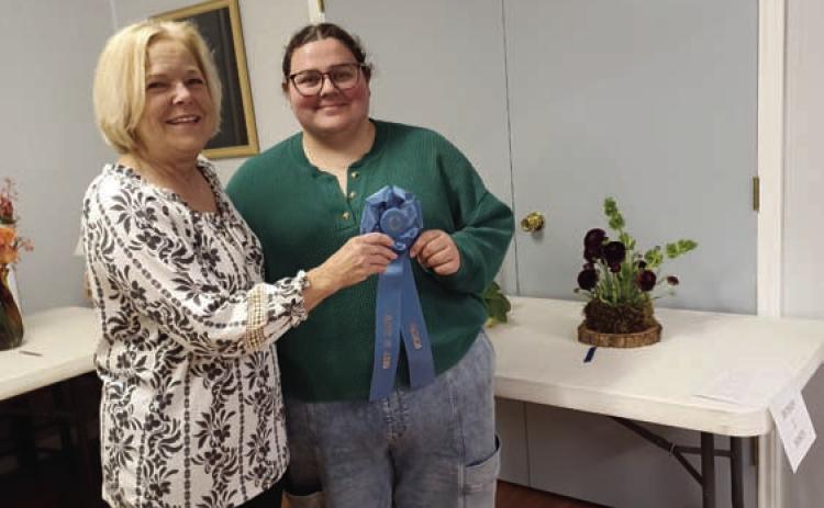 Holly Hines, at right, garnered the Best in Show Award for her arrangement using dark-purple ranunculus. Sheri Stone presented the award on behalf of the L-M Garden and Civic Club. COURTESY PHOT0