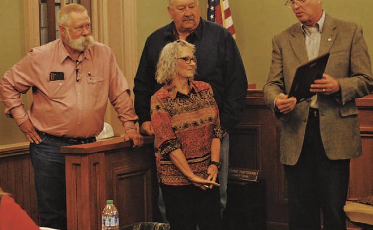 The Lampasas County Commissioners Court presented retiring County Clerk Connie Hartmann with a plaque to recognize her service over the last four decades. Standing behind Hartmann are Precinct 3 Commissioner Lewis Bridges, at left, and Precinct 4 Mark Rainwater as County Judge Randy Hoyer, at right, reads from Hartmann’s plaque. HUNTER KING | DISPATCH RECORD