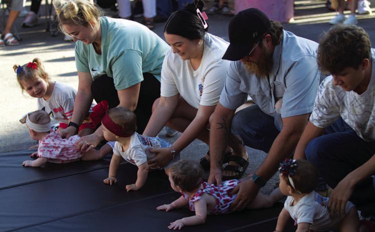Parents help line up their baby racers before Diaper Derby action gets underway outside the Lampasas County Courthouse on Friday morning. HUNTER KING | DISPATCH RECORD