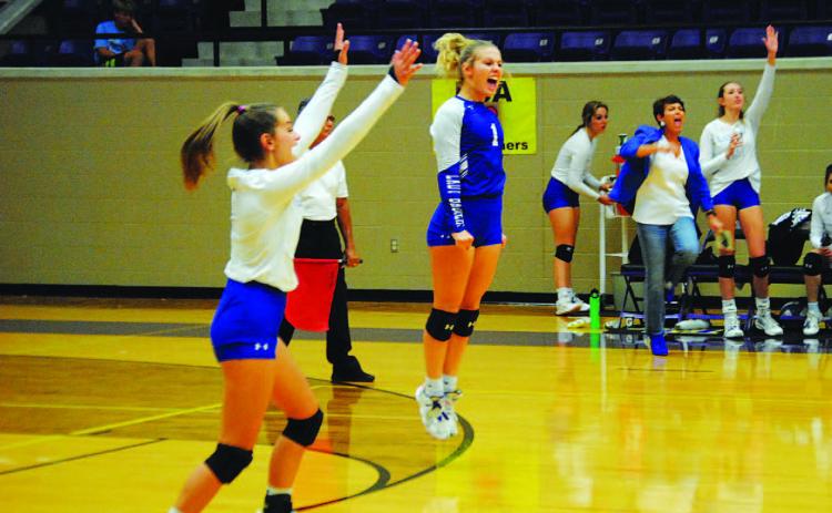 Kayli Syx, left, and Bre Quarles celebrate a point during the playoff matchup. Head coach Christy Wiley and the bench also show their excitement. HUNTER KING | DISPATCH RECORD