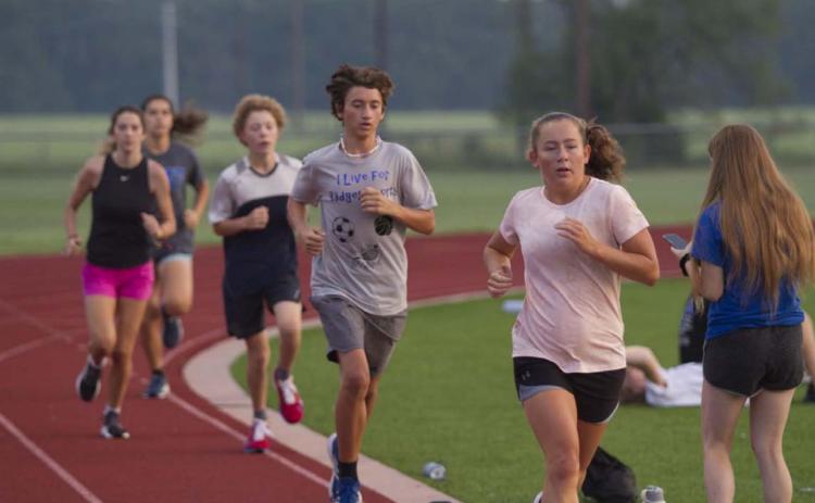 Tyler Ecker and Abby Valdez race around the track at Lampasas High School during cross country practice. HUNTER KING | DISPATCH RECORD