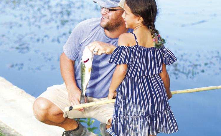 Jillian Rincones and her dad Nathan Rincones pose with her 13-inch bass at the fishing derby. HUNTER KING | DISPATCH RECORD