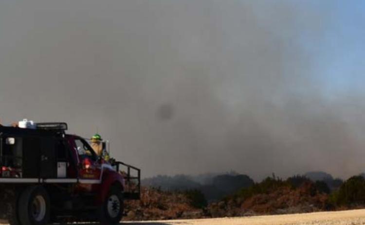 Volunteer firefighters Luke White (on front bumper) and Carlos Garcia (driving, not pictured) arrive in a brush truck at a fire on County Road 2234 on Thursday. MADELEINE MILLER | DISPATCH RECORD