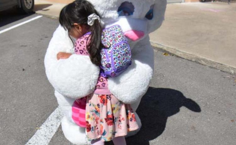 Two-year-old Lampasan Zaria Eva Ashley Rivera hugs the Easter Bunny tightly during the Aware Central Texas Easter kit drivethrough at the Lampasas Police Department headquarters. MONIQUE BRAND | DISPATCH RECORD
