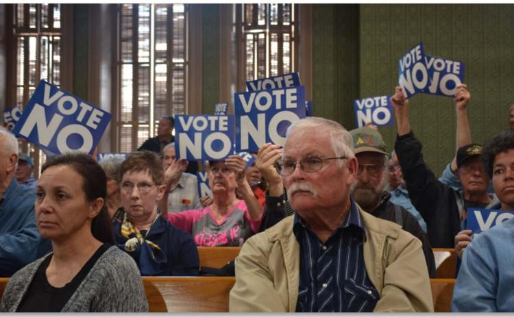 County residents hold up signs asking the Commissioners Court to vote “No” on a reinvestment zone for 3,800 acres of land where a solar farm could be constructed that would cover about 1,500 acres within the tract. MONIQUE BRAND | DISPATCH RECORD