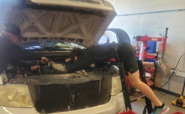 Nathan Abken, at right, leans over the hood of a pickup as he works on an engine as part of his training this spring in the Lampasas High School Auto Tech II class. FILE PHOTO
