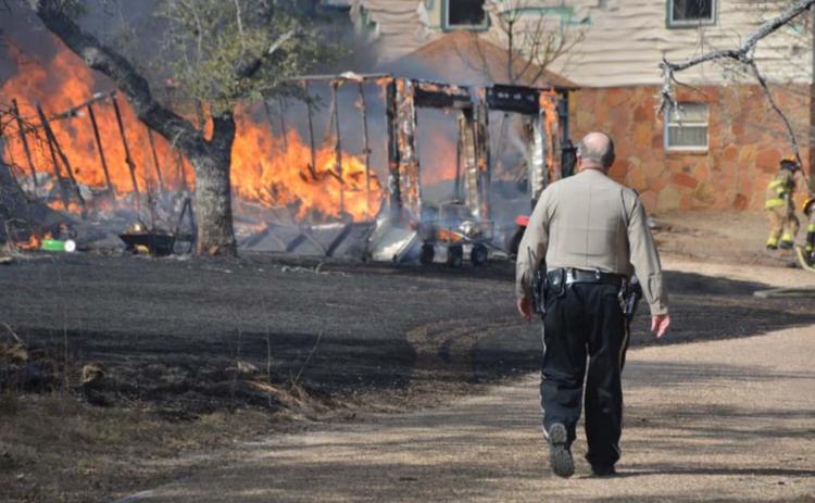 A deputy walks alongside County Road 1025 to aid other first responders at last week’s structure fire. MONIQUE BRAND | DISPATCH RECORD