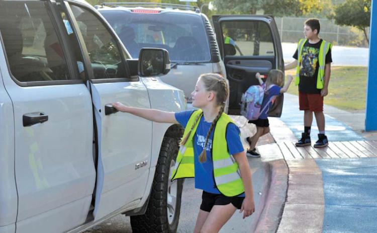 First-year World Changer McKaylynn McKinnon prepares to open the door for a fellow student during morning drop-off patrol. erick mitchell | dispatch record