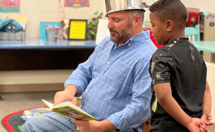 Lampasas ISD school board member Jeff Rutland, decked out as Johnny Appleseed, reads a book alongside first-grader Eli Vazquez on Monday. court esy photo