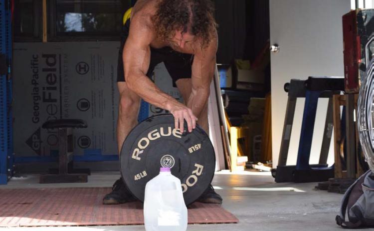 A functional fitness athlete does an open-air workout on a hot summer’s day, but not without his gallon jug of water. The human body can lose several pounds of water through sweat and exhalation during high activity. ALEXANDRIA RANDOLPH | LAMPASAS DISPATCH RECORD
