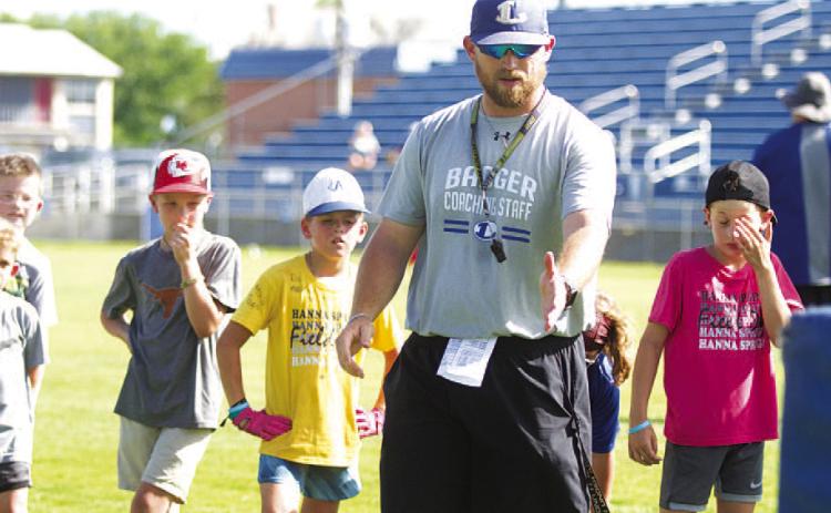 Assistant coach Chance Evans teaches a pass rush drill to campers on Wednesday. HUNTER KING | DISPATCH RECORD