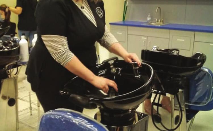 Elizabeth Casper demonstrates use of the shampoo bowls during the salon open house on Dec. 8. VERONICA BUTLER | DISPATCH RECORD
