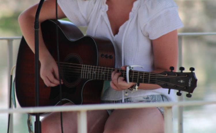 Hometown girls Daelyn Ellis plays her guitar and sings “Those Boots,” written by Lainey Wilson, during music in the park on Wednesday. joycesarah mccabe | dispatch record