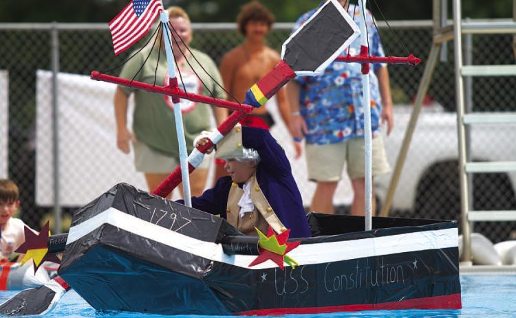 Case Jones rows the U.S.S Constitution across the Hanna Springs Swimming Pool during the Cardboard Regatta event on Saturday. HUNTER KING | DISPATCH RECORD